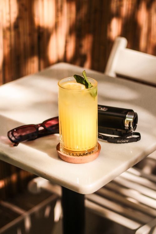 Free A glass of chilled lemonade with mint on a sunlit cafe table. Stock Photo