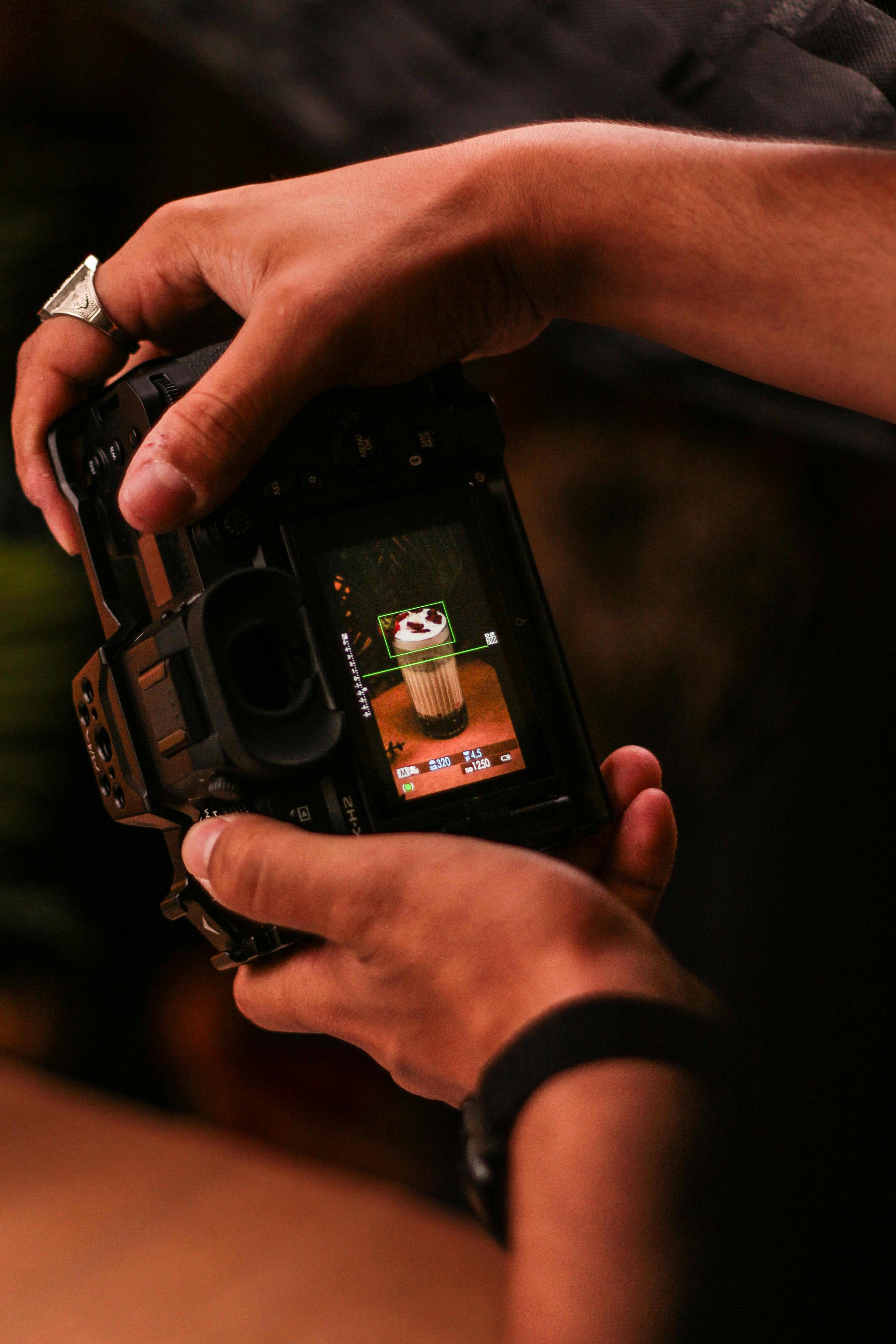 A photographer fine-tunes DSLR settings to capture a latte art coffee on screen.