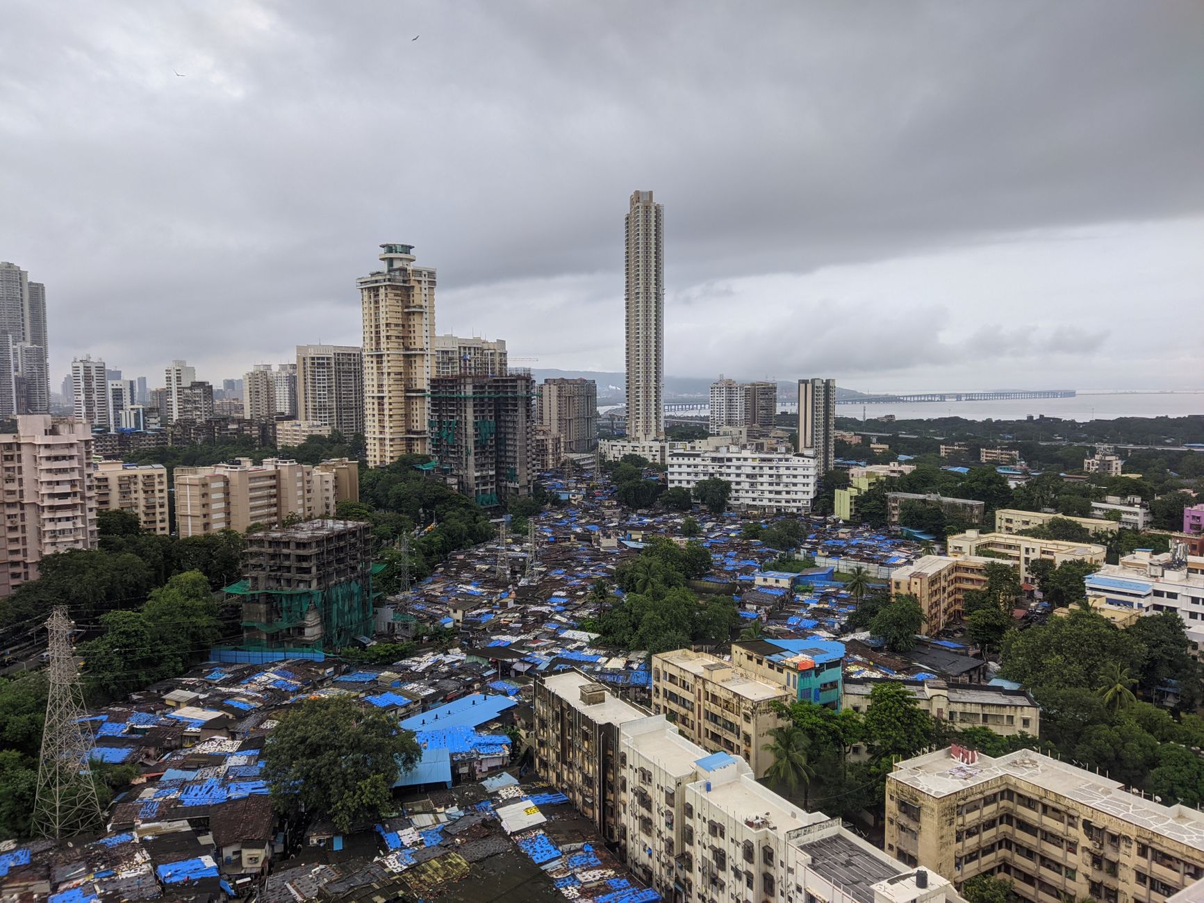 Mumbai monsoon traffic moving through flooded streets beside glowing storefronts and umbrellas