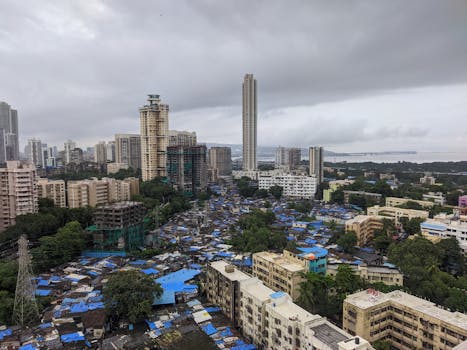 A breathtaking aerial view of Mumbai's dynamic skyline blending urban skyscrapers with local settlements under cloudy skies.