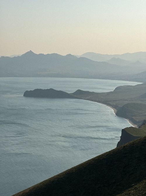 Free Serene coastline with distant mountains and calming twilight atmosphere. Stock Photo