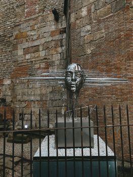 A striking metal sculpture set against an ancient brick wall highlighting urban art.