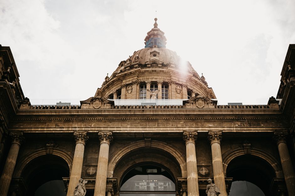 Stunning low-angle shot of a grand historical building with a dome under bright sky.