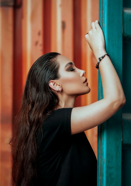 A stylish portrait of a woman with long brown hair posing thoughtfully indoors.
