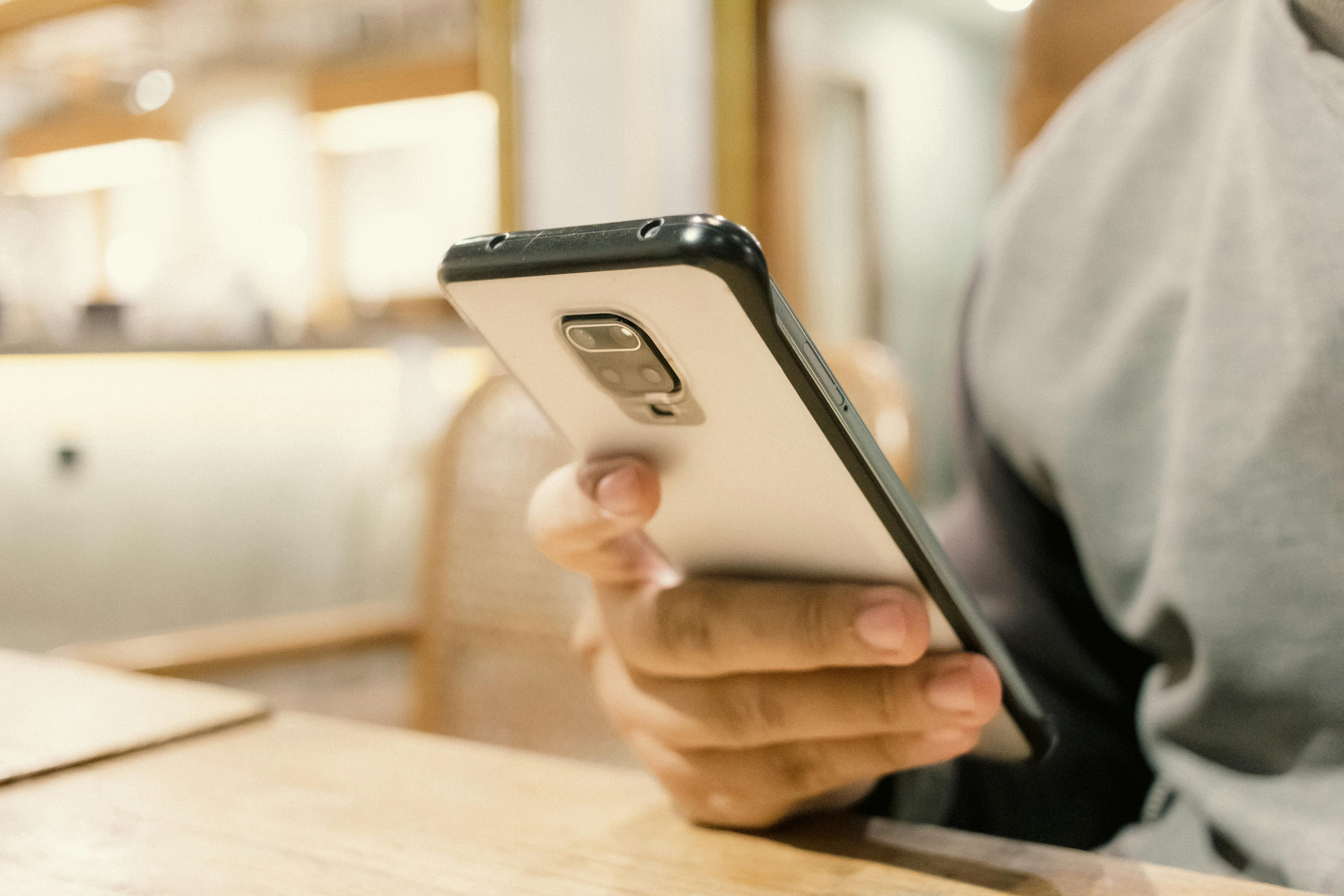 a person holding a cell phone in front of a wooden table