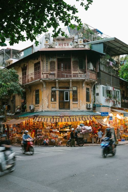 Free A vibrant market at a historic building intersection with motorbikes on a busy day. Stock Photo