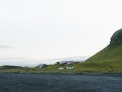 在明亮的天空下，古色古香的房屋坐落在冰岛郁郁葱葱的乡村里