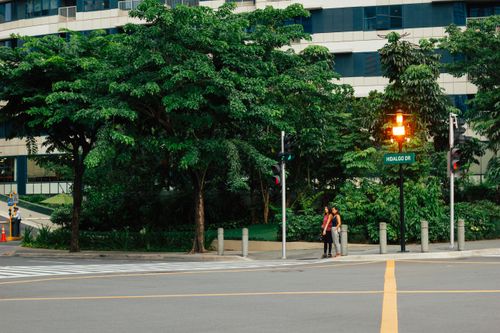 Free City street intersection with pedestrians, greenery, and modern buildings. Stock Photo