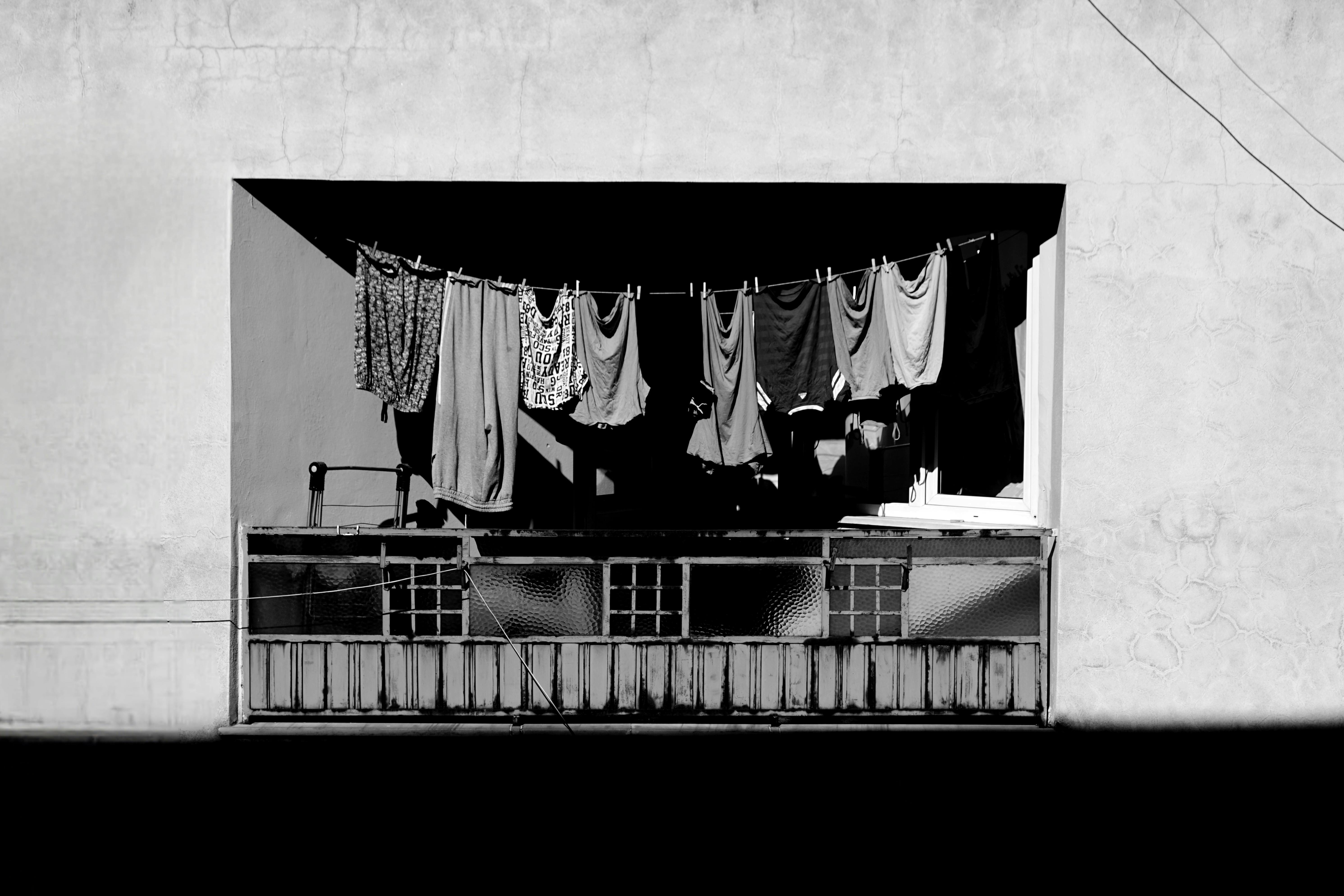 Monochrome photo of a balcony with clothes hanging out to dry in an urban setting.