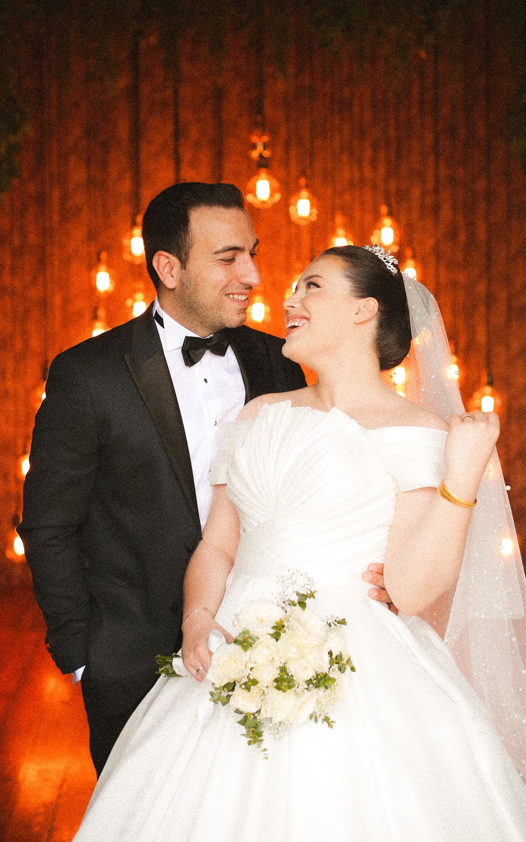 Happy bride and groom sharing a loving moment in a warmly lit indoor setting.