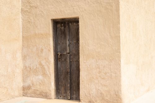 Free A rustic wooden door set within a rough, textured wall, emitting a timeless, vintage feel. Stock Photo