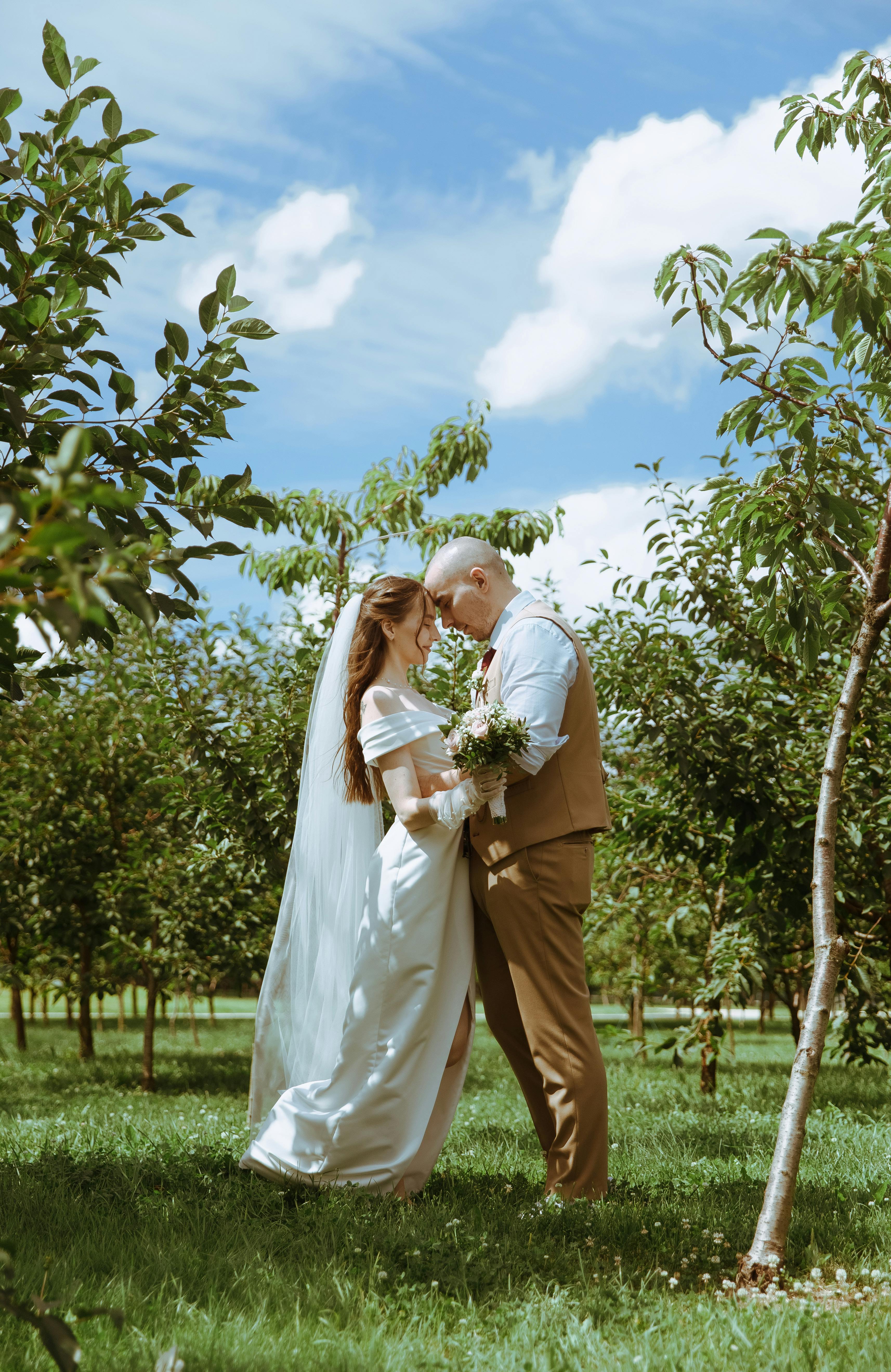 a bride and groom kiss in an orchard