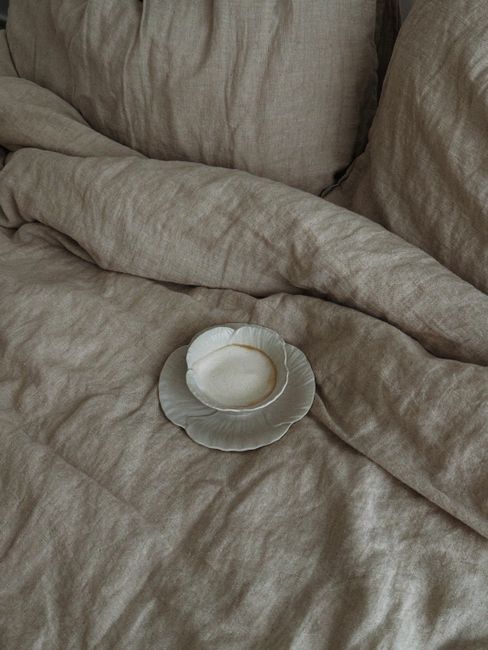A rustic bedroom setting featuring vintage fabric bedding and a ceramic cup.