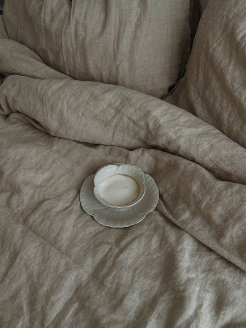 Free A rustic bedroom setting featuring vintage fabric bedding and a ceramic cup. Stock Photo
