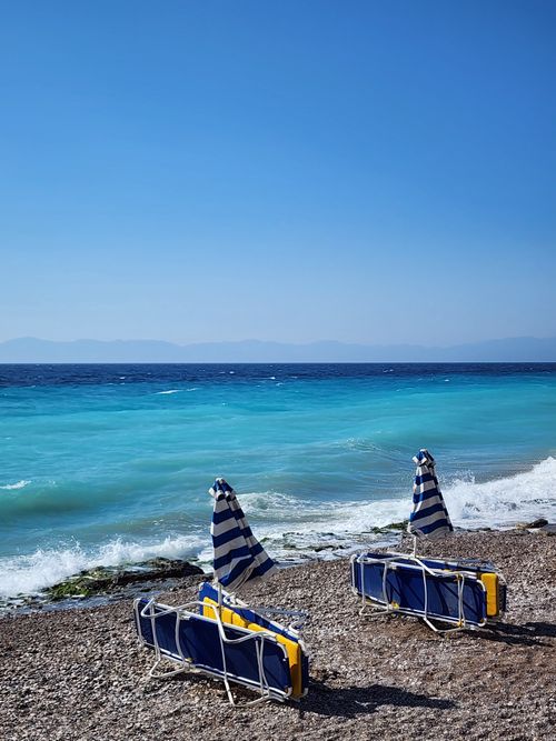 Free Relaxing beach view on Rodos, Yunanistan with blue chairs and sea. Stock Photo