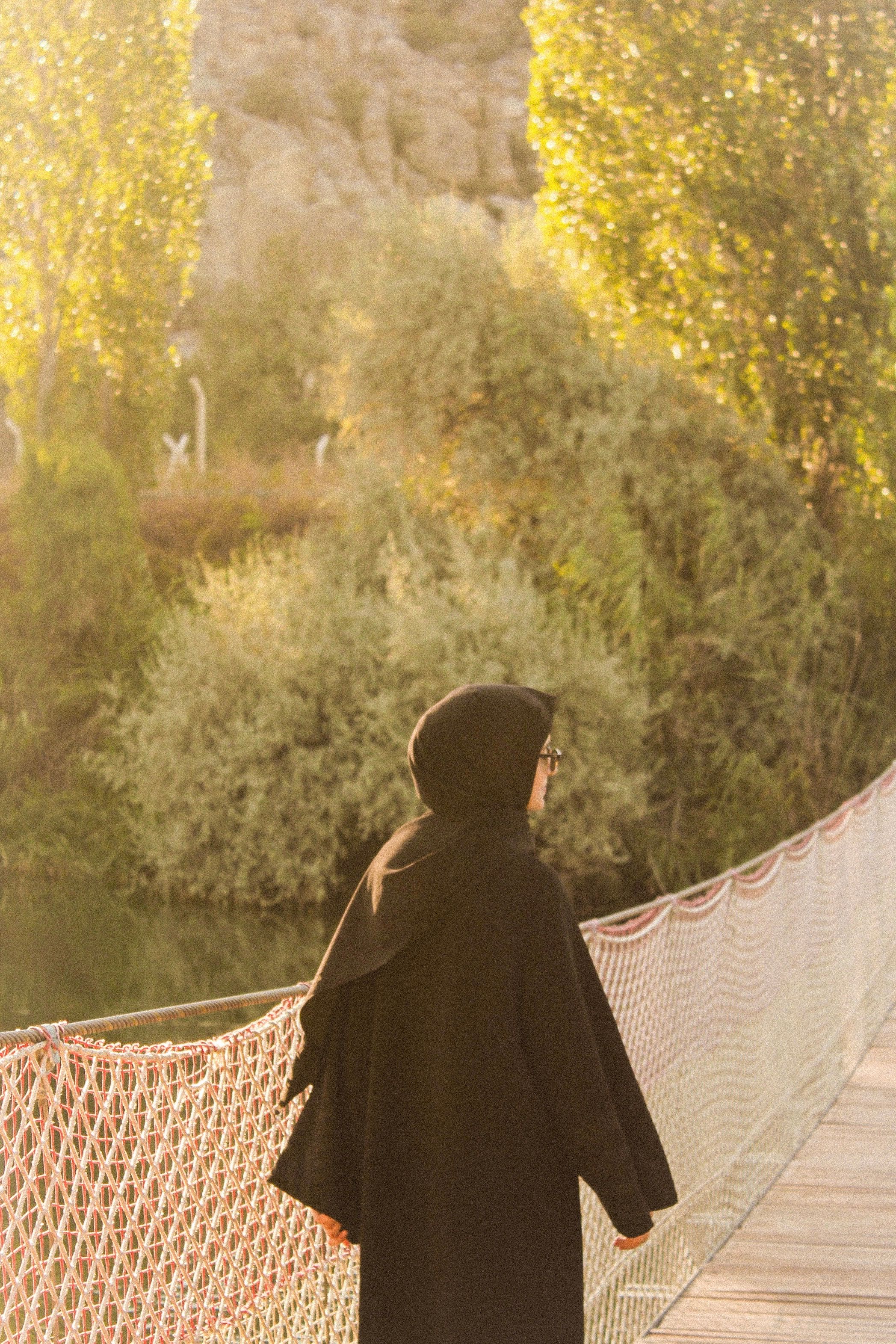 A woman in a black coat walks across a bridge · Free Stock Photo