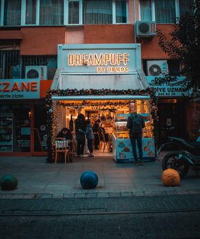 A lively night scene at a street cafe in Istanbul with people enjoying pastries under warm lights.