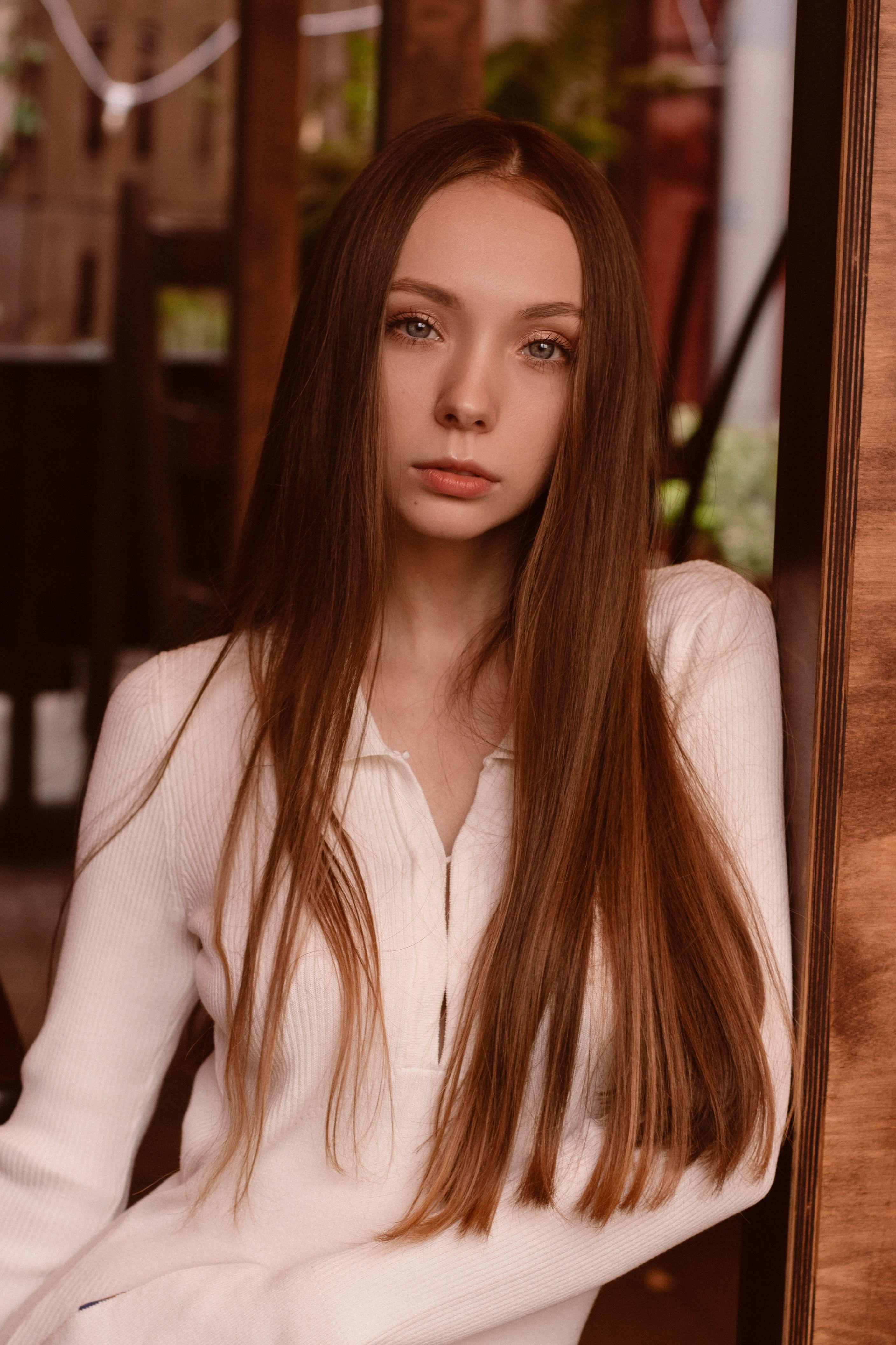 Elegant portrait of a young woman in a white sweater with long hair indoors.