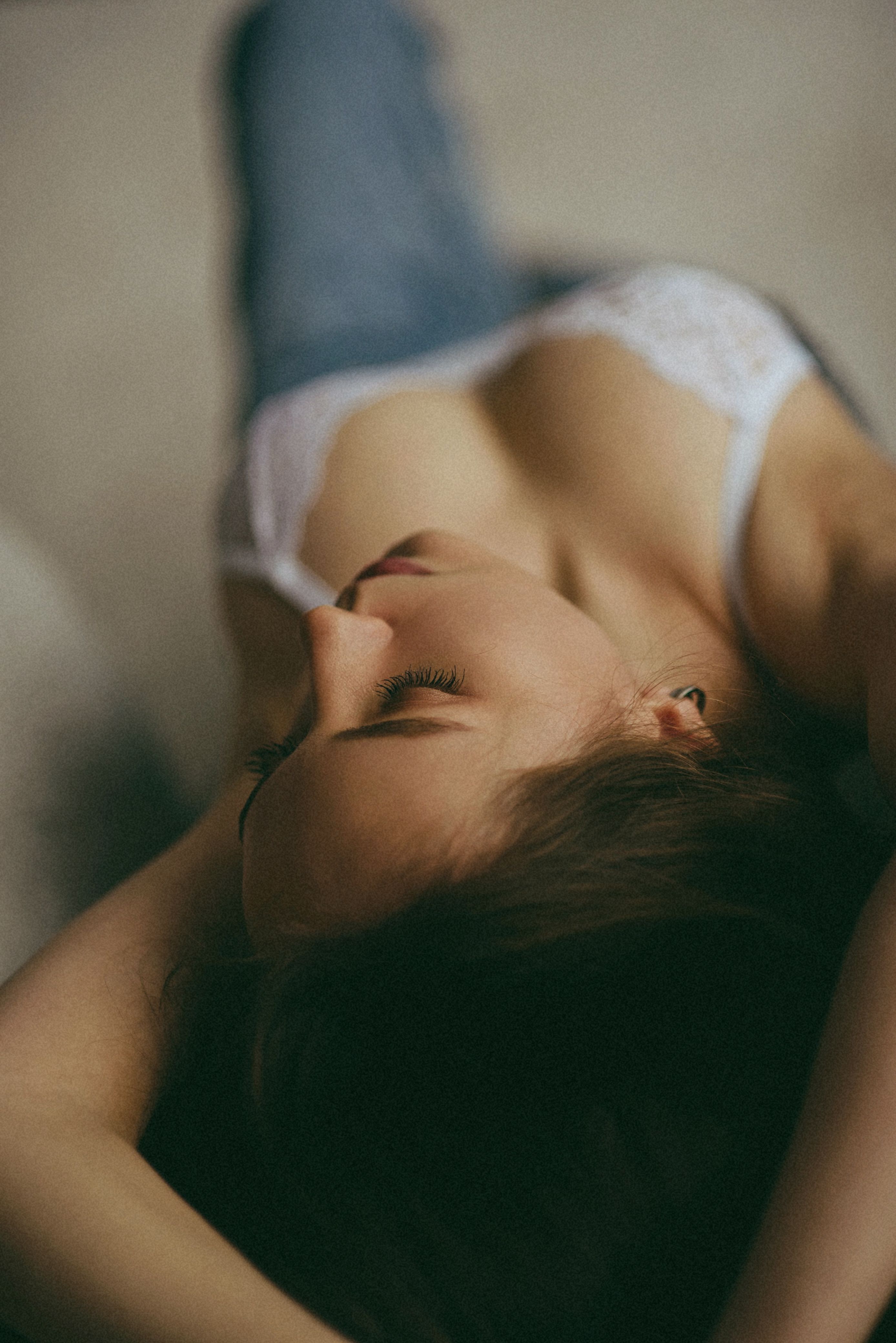 A serene image of a woman reclining indoors in lingerie, capturing a moment of relaxation and intimacy.