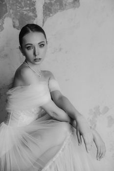 Timeless black and white portrait of a bride in an elegant gown against a textured wall.