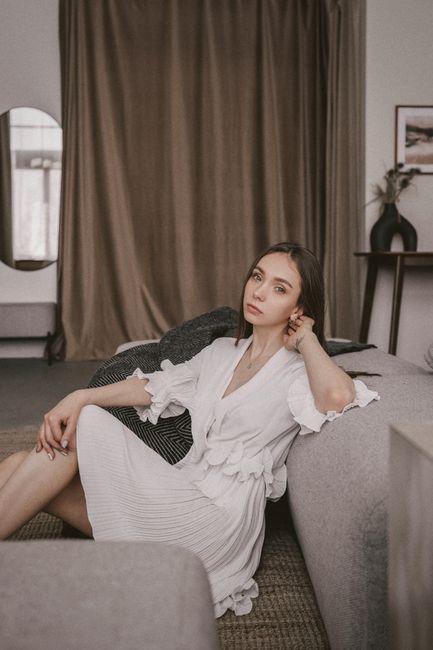 Serene portrait of a woman in a stylish living room setting, emphasizing relaxation and fashion.