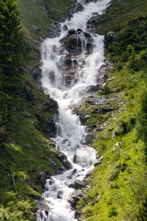 Free Stunning waterfall cascading through lush greenery in Heiligenblut, Austria, during summer. Stock Photo