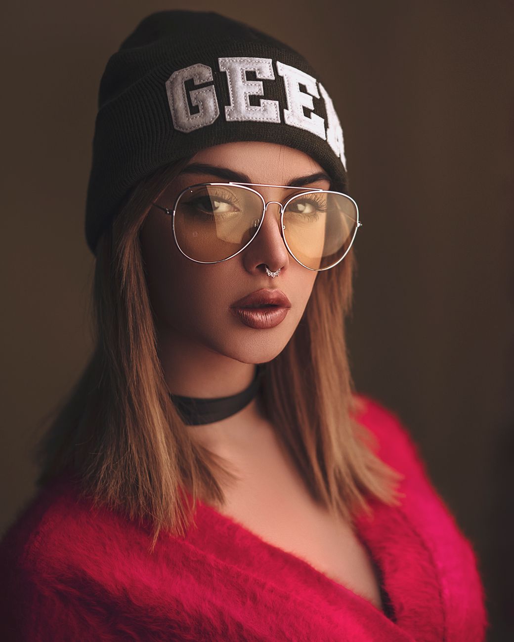 A fashionable woman wearing a beanie and sunglasses in a modern portrait.