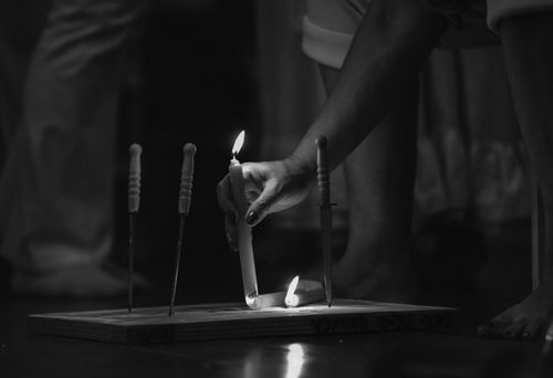 Free A hand lights candles in a dimly lit room, creating a moody atmosphere. Stock Photo