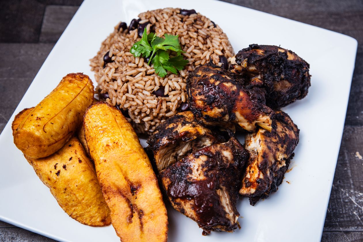 Traditional Caribbean jerk chicken plate with rice and beans and fried plantains