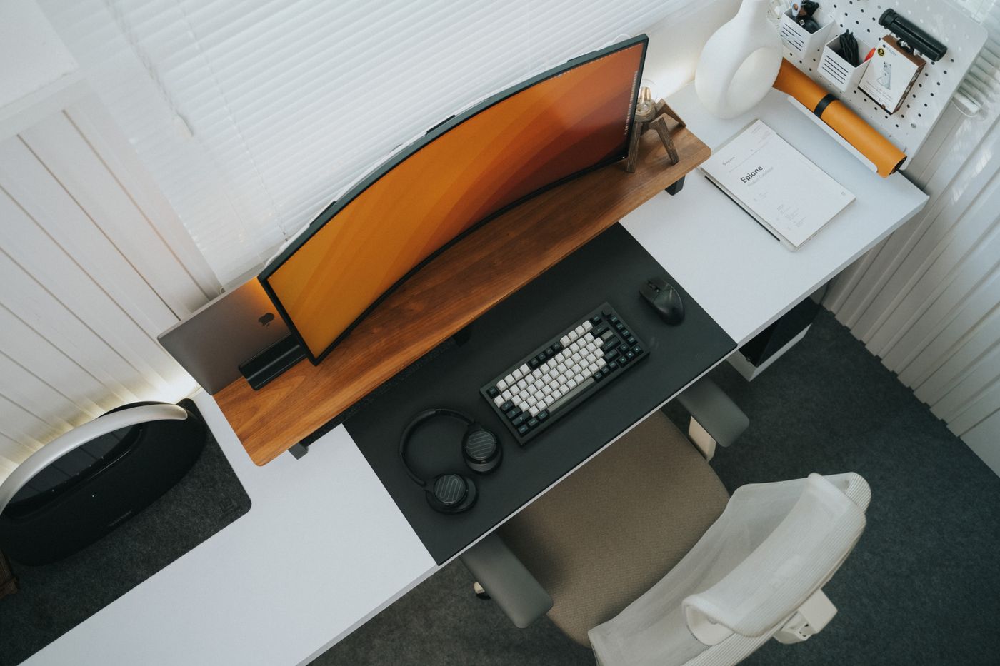 Top view of a stylish modern office desk setup featuring a curved monitor and keyboard.