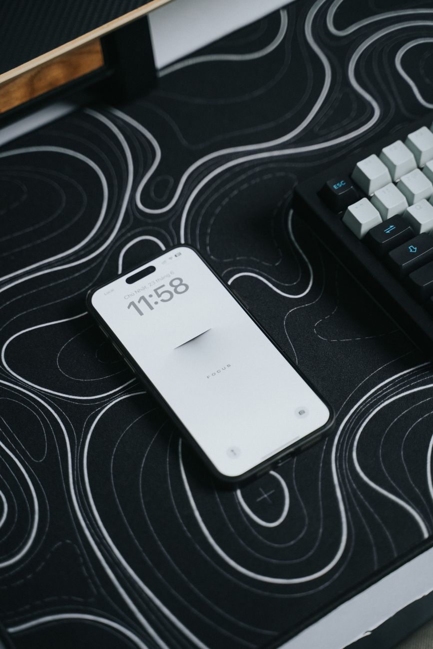 Sleek smartphone with a minimalist display beside a mechanical keyboard on a patterned desk mat.. pexels, sleek, smartphone
