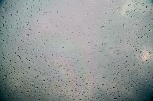 Free A serene view of raindrops on glass with a soft sky reflection creating an abstract texture. Stock Photo