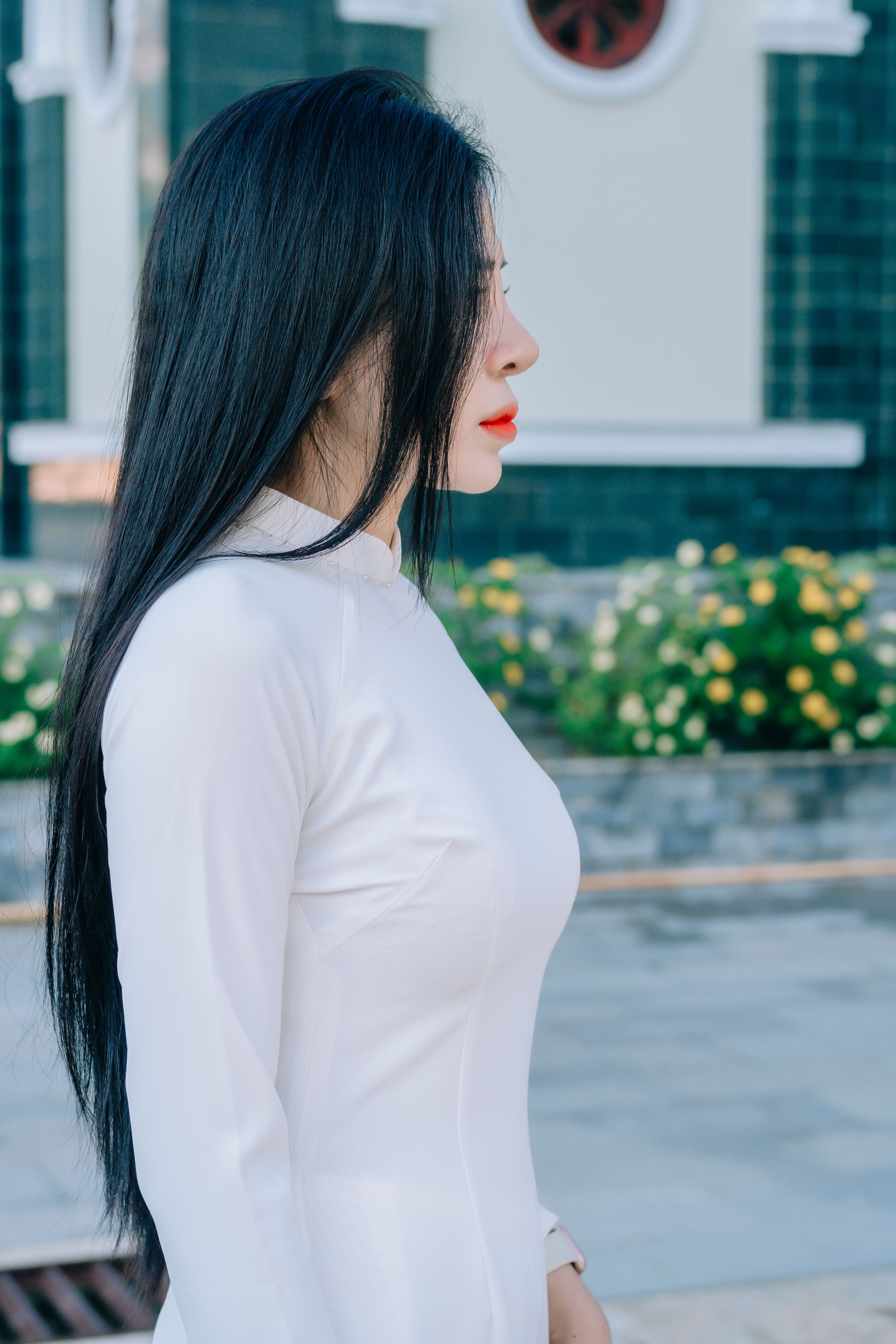 Profile of a young woman in white, outdoors with a vibrant floral background.