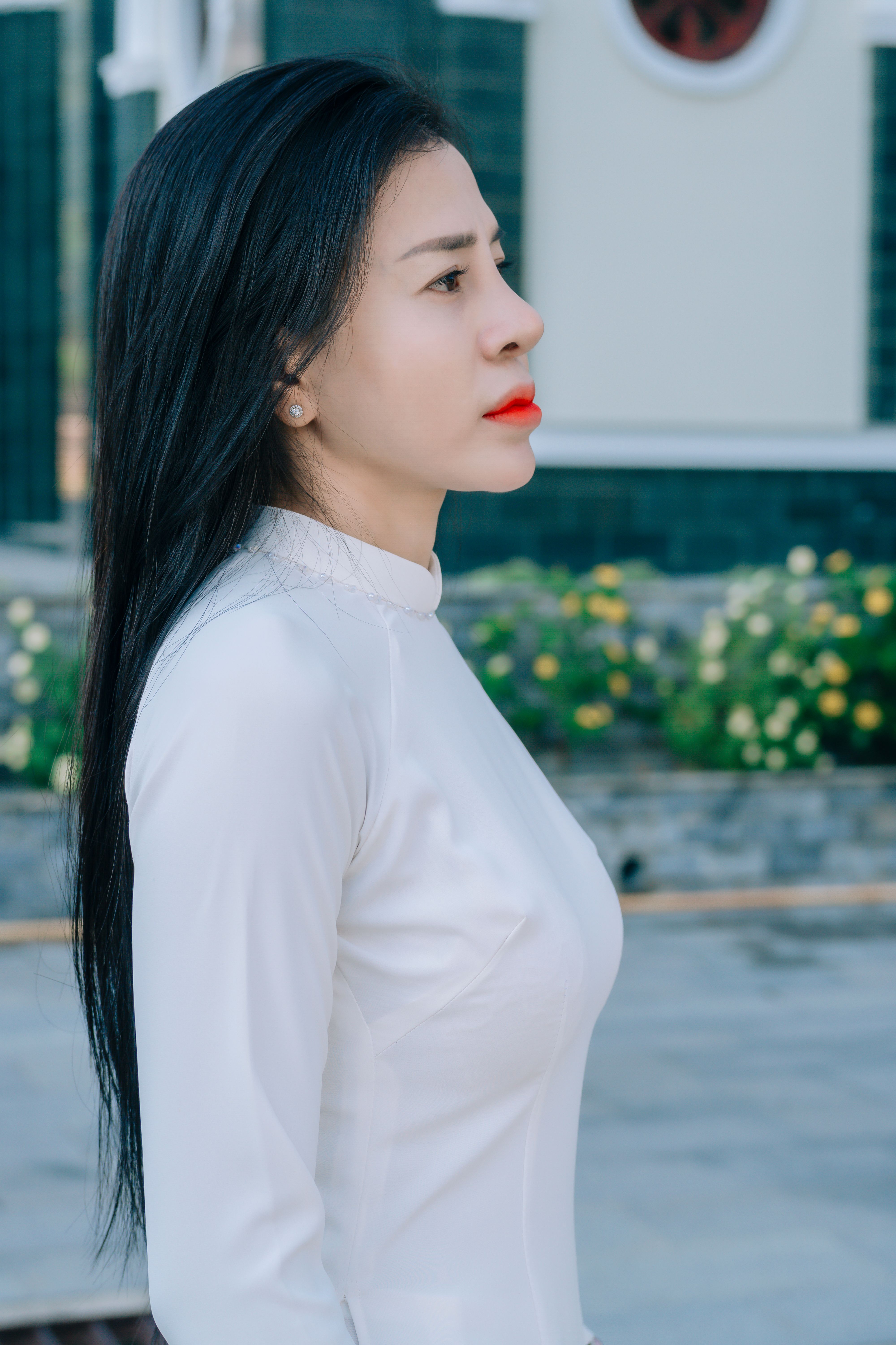 Portrait of a young woman in a white dress standing outdoors.