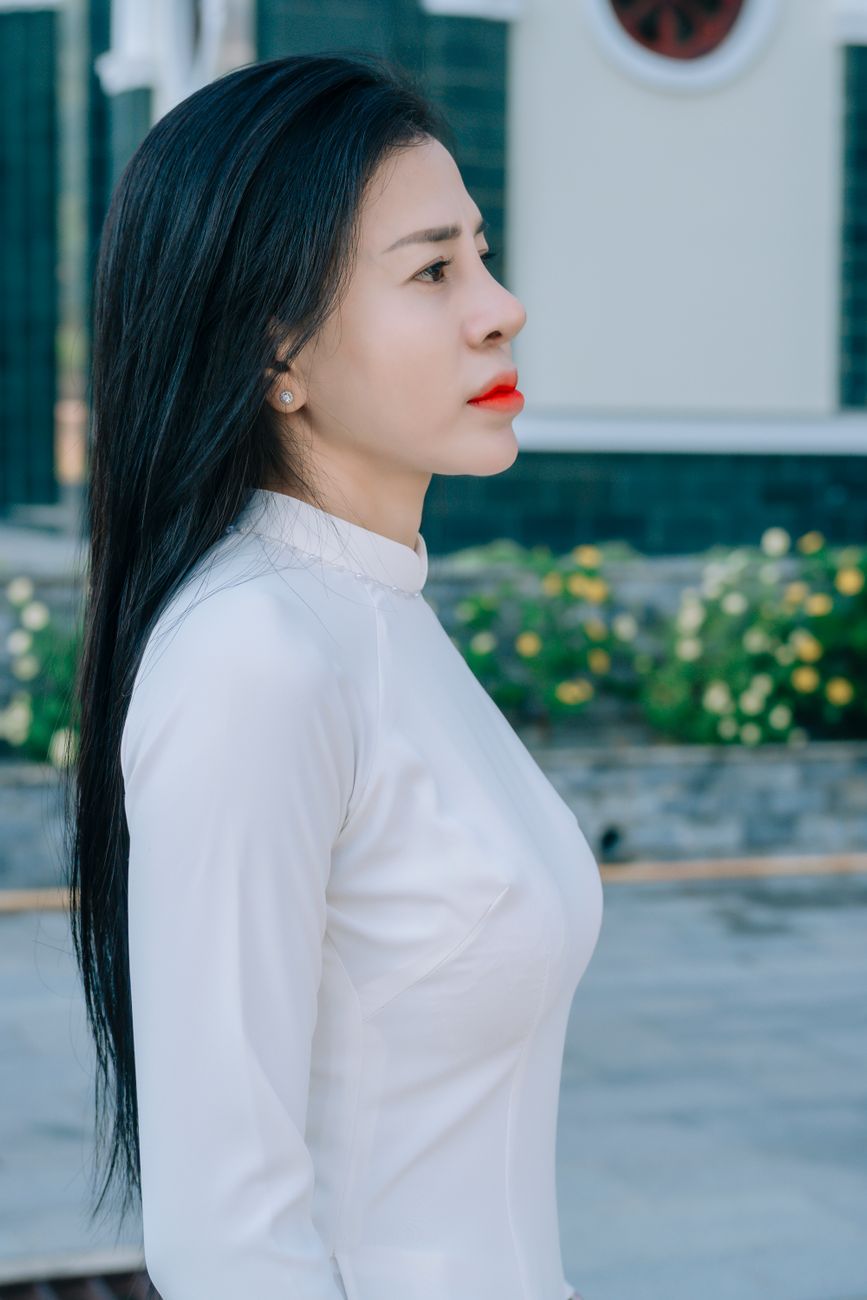 Portrait of a young woman in a white dress standing outdoors.