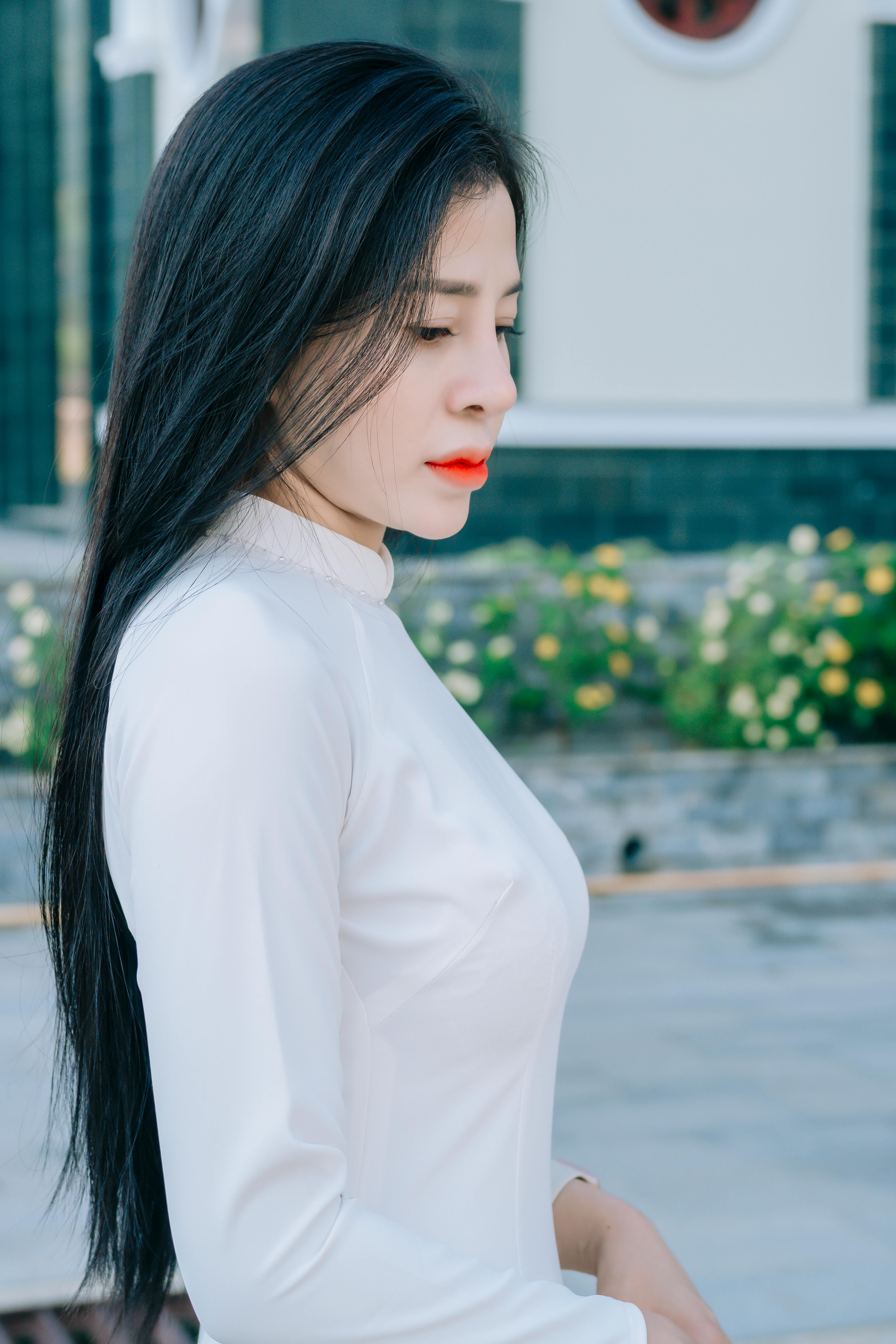 Side profile of a young woman in white traditional attire standing outdoors, exuding elegance and grace.