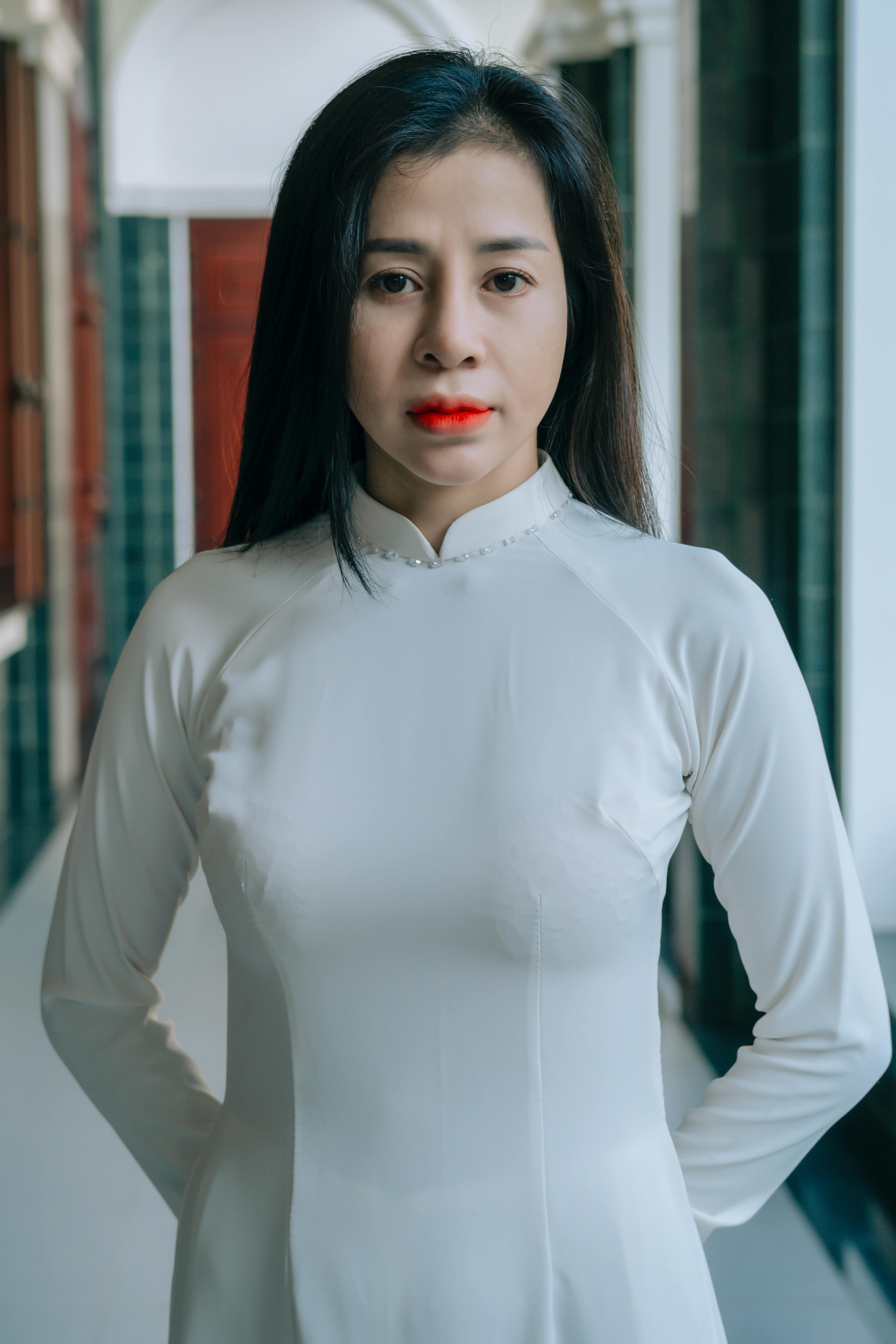 Portrait of an elegant woman in a white Ao Dai, standing indoors with serene expression. Perfect for fashion and cultura