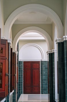 An elegant hallway featuring arches and a classic wooden doorway, perfect for luxury settings.