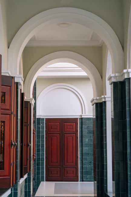 An elegant hallway featuring arches and a classic wooden doorway, perfect for luxury settings.