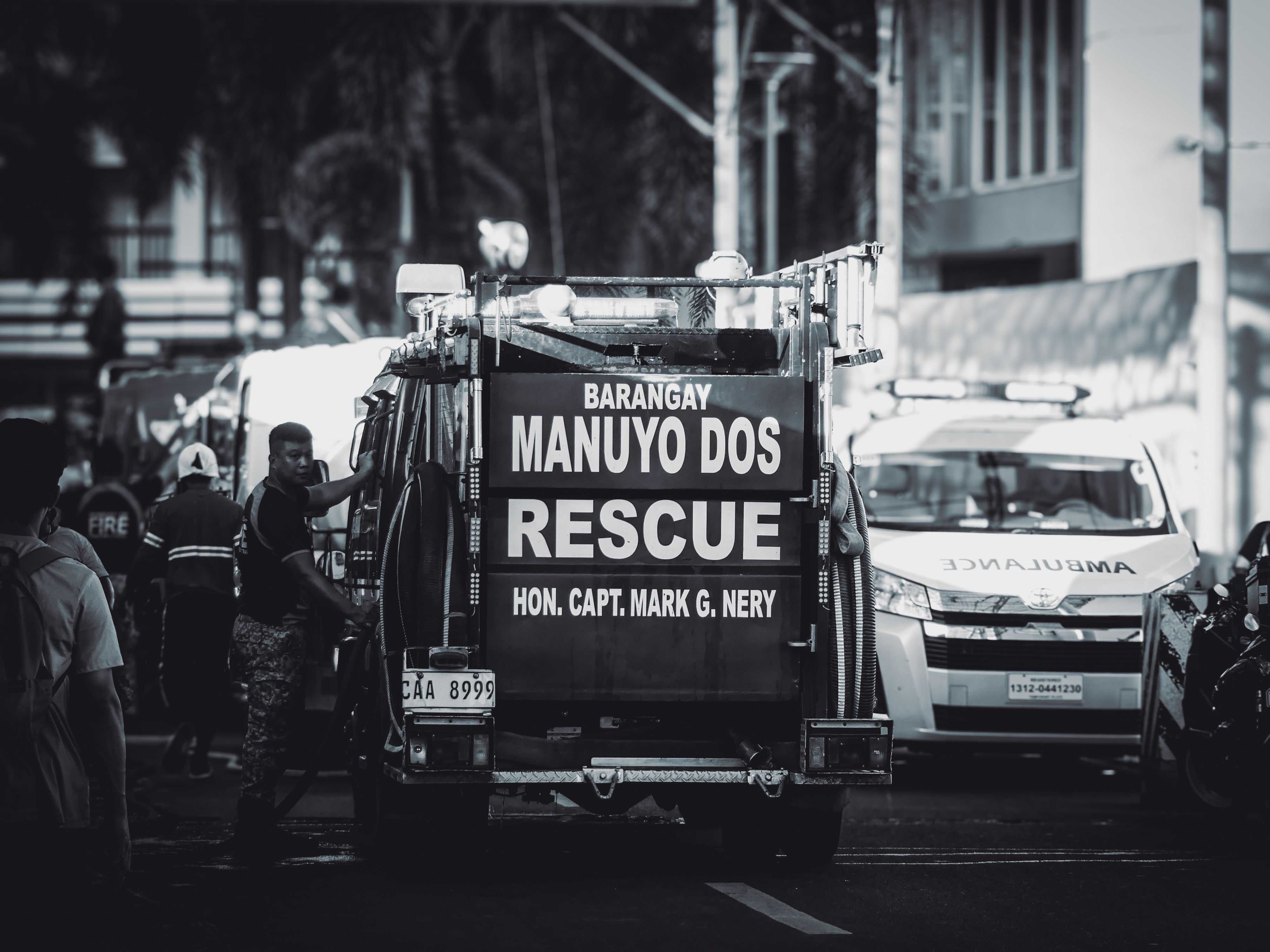 Monochrome scene featuring rescue vehicles and personnel on a busy urban street.