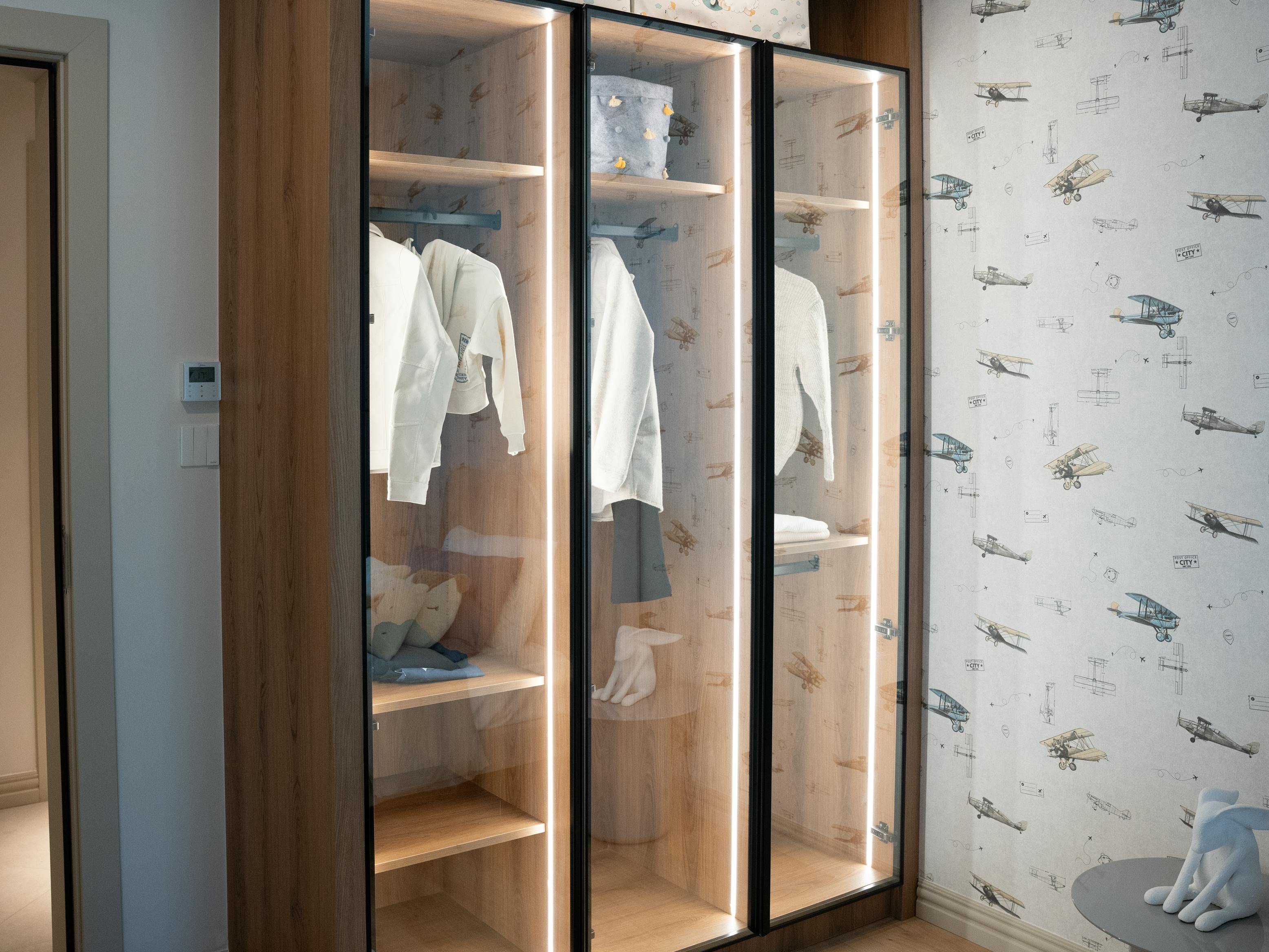 Wooden wardrobe with glass doors in modern home interior, showcasing minimalist fashion style.