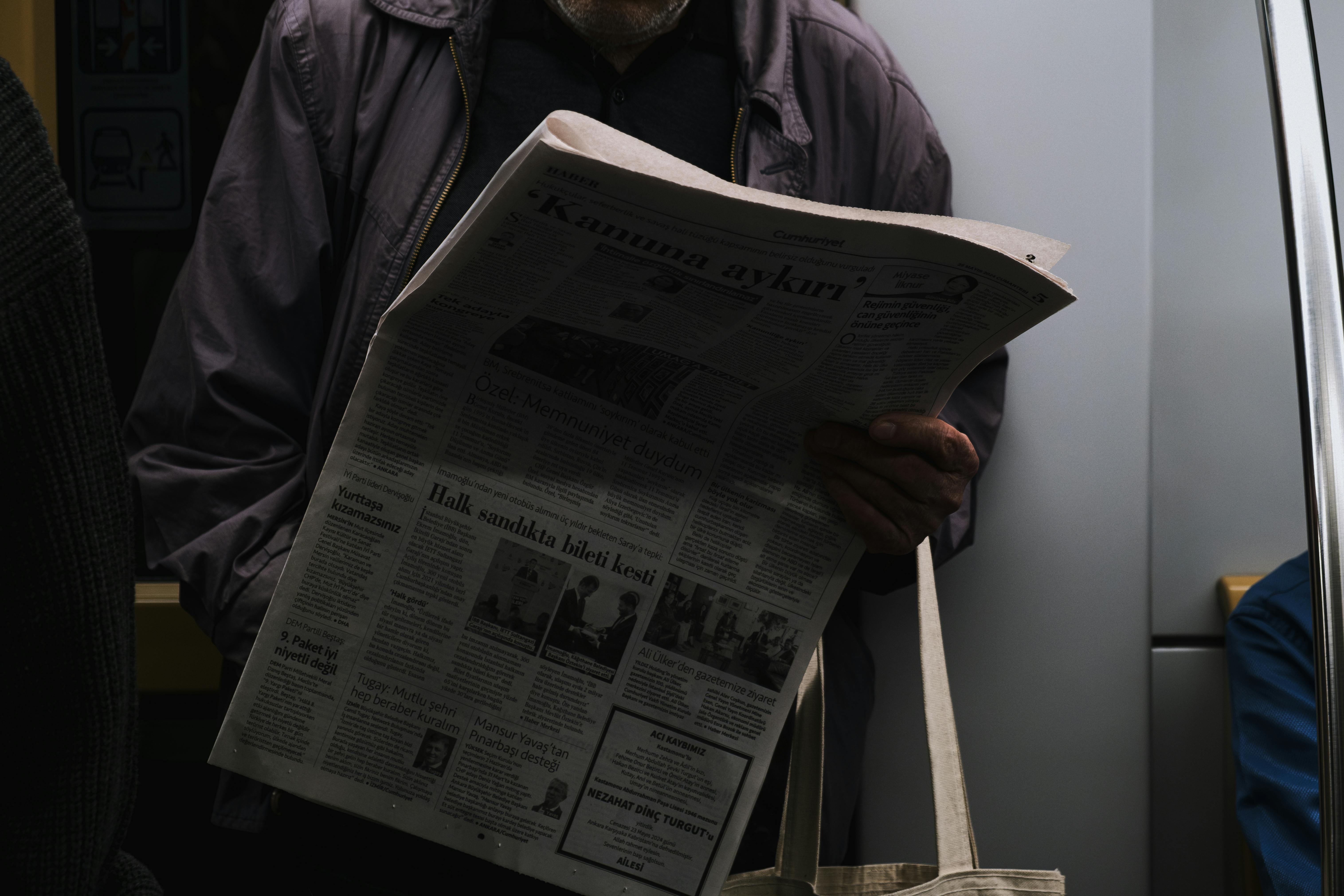 a man reading a newspaper on a subway