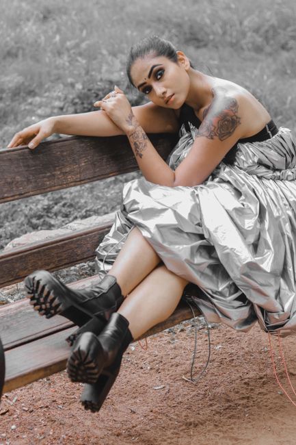 Stylish woman with tattoos in a silver dress sitting on a bench in New Delhi.
