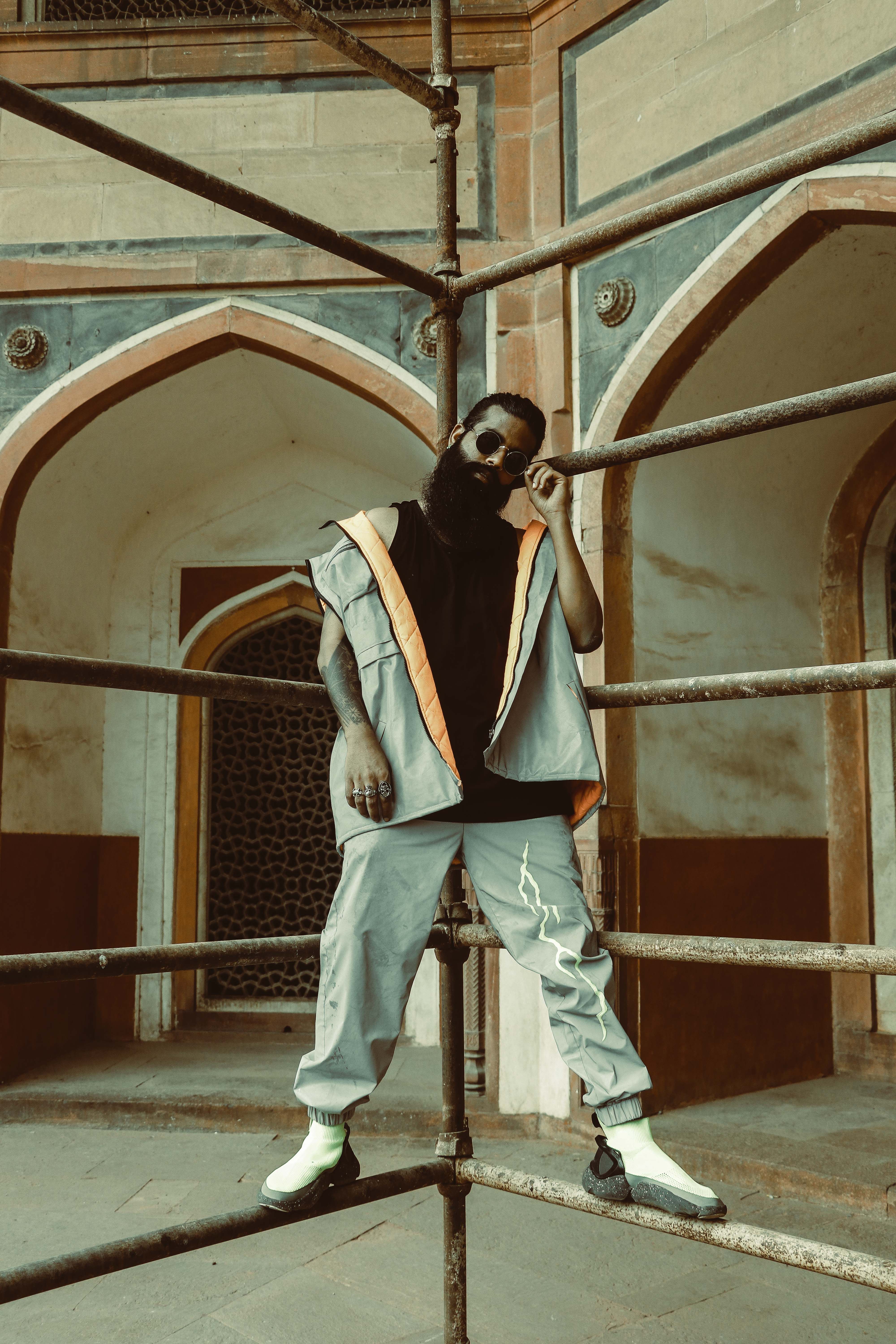 Stylish man posing against historic architecture in New Delhi, blending modern fashion with classic charm.