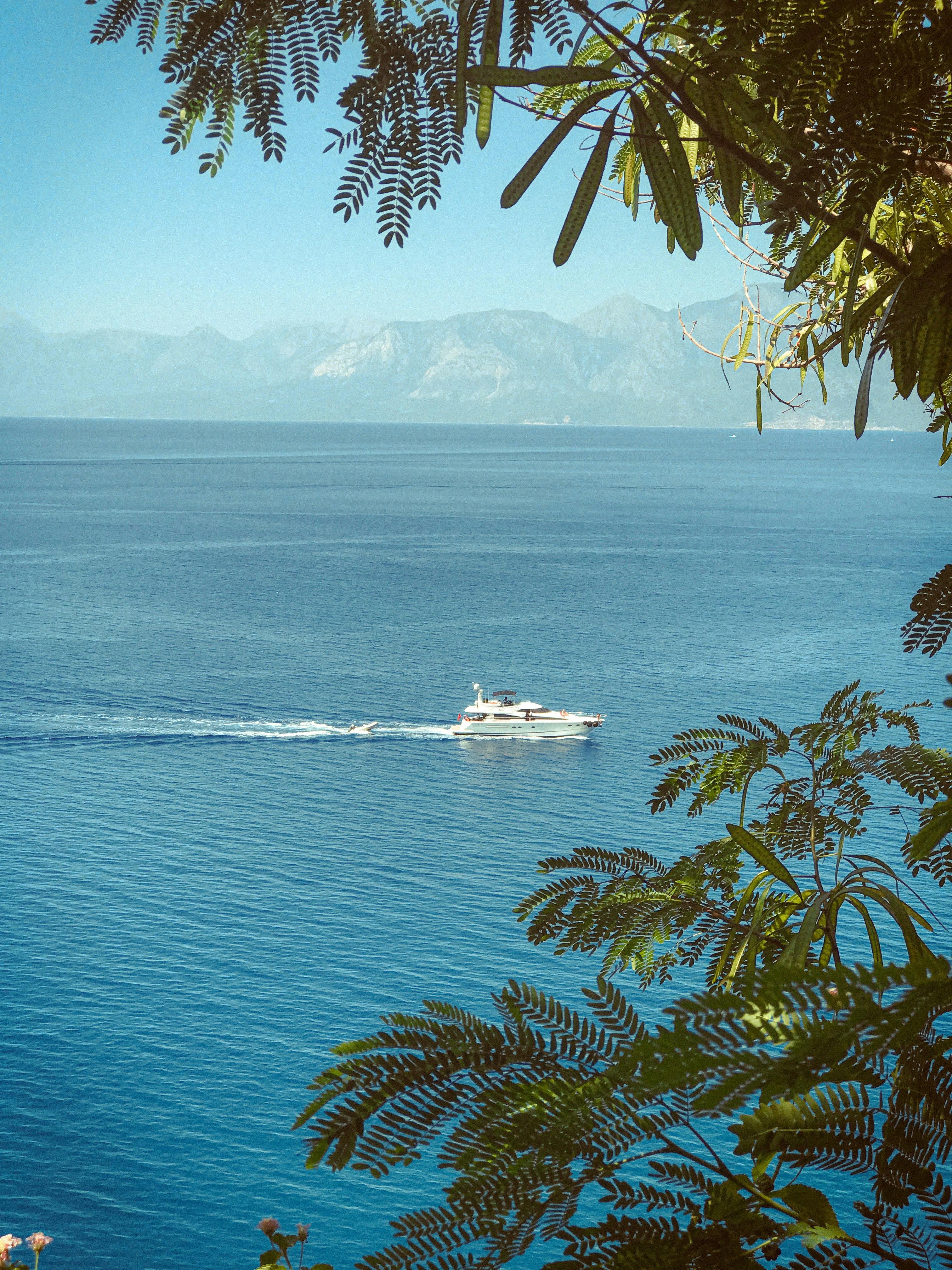 A tranquil view of a boat cruising the Mediterranean Sea with distant mountains near Antalya, Türkiye.