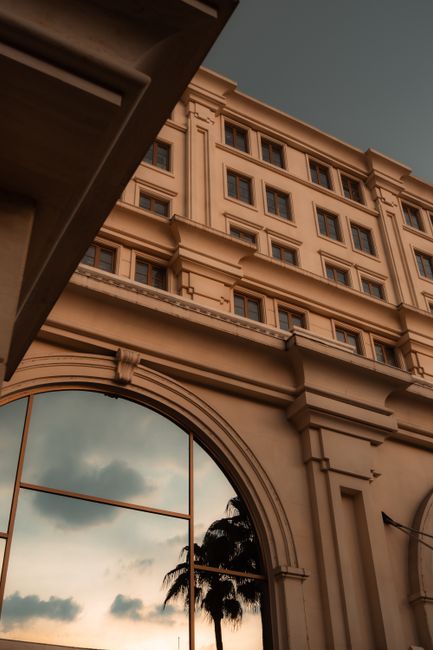 Elegant classical building facade with sunset reflections on glass.