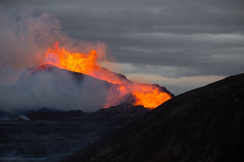 Stunning capture of a volcanic eruption, spewing molten lava and smoke under a cloudy sky.