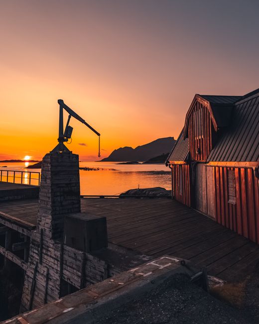 Beautiful sunset view over the ocean with a rustic wooden cabin by the waterfront dock.