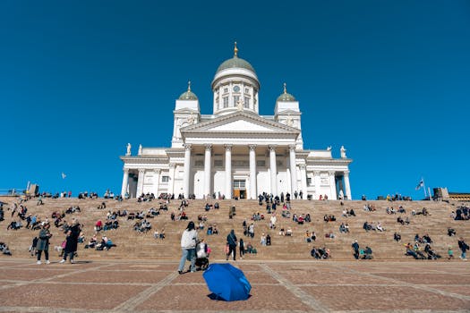 People gather on the steps of Helsinki Cathedral under a bright blue sky, showcasing Finland's iconic architecture.