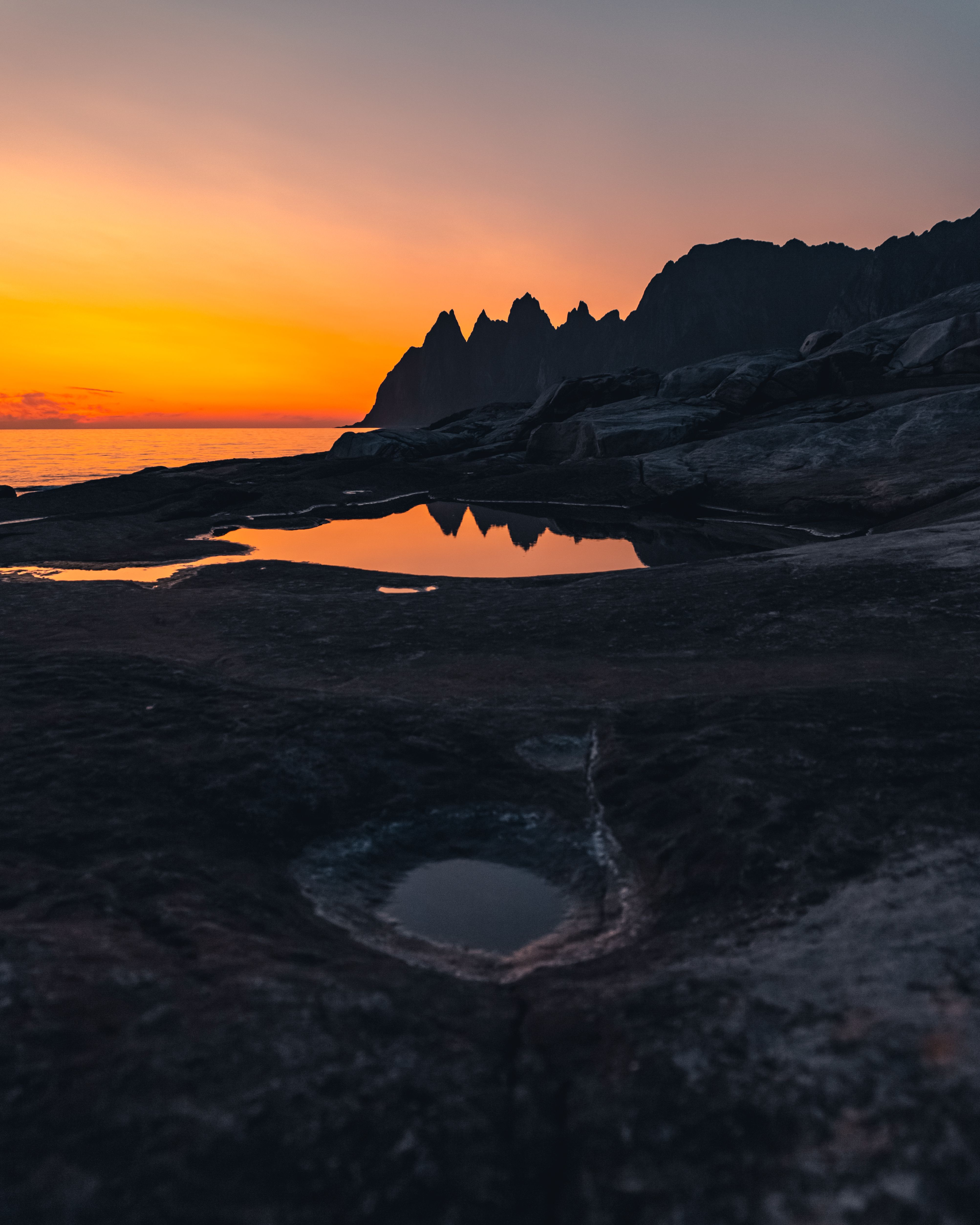 岩石海岸上，日落令人惊叹，海面倒映着余晖，呈现出一片宁静的海景